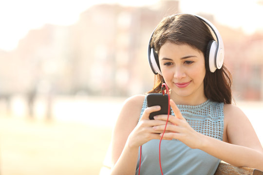 Girl searching songs and listening music with headphones