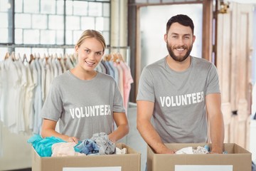 Portrait of smiling volunteers separating donations clothes 