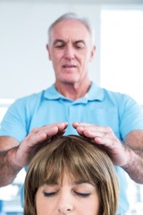 Male therapist performing reiki over woman
