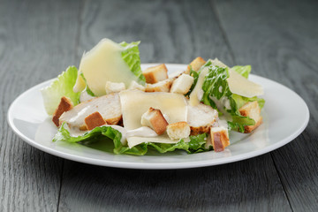 Caesar salad with chicken on wooden table