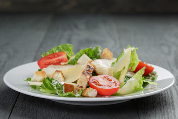 Caesar salad with chicken on wooden table