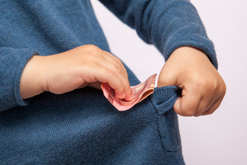 Small child's hand puts ten euro banknote in his pocket