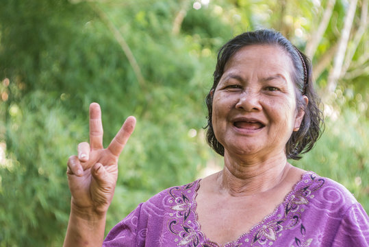 Old Thai woman smiling and showing V sign
