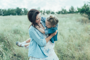 The young mother and daughter on green grass background 