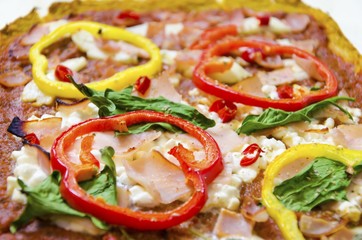Pizza toppings. Oven baked pizza topped with halloumi, cottage, mozzarella cheese, spinach, turkey, ham, red and yellow peppers, chili, basil and tomato sauce with selective focus on pepper.