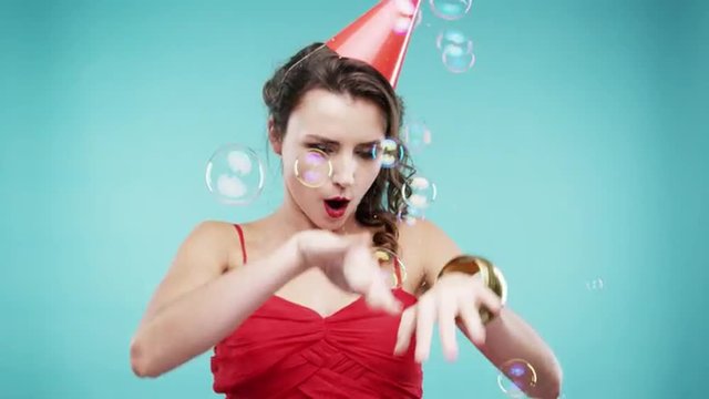 Crazy face drunk woman dancing in bubble shower slow motion photo booth blue background