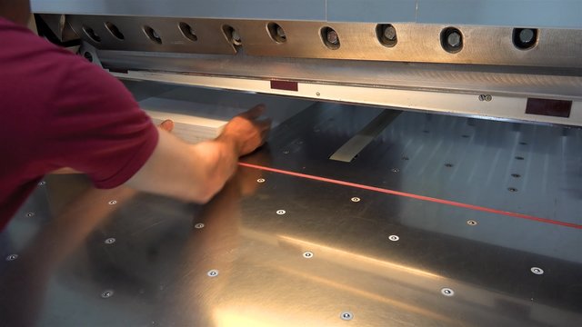 Modern paper guillotine in commercial printing industry (industrial knife cutter), Operator cut sheet of paper for offset print magazine, UHD 4K stock footage