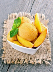 Peach sorbet with mint in white bowl on rustic table