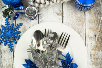 Christmas table setting in silver and blue tone on wooden table