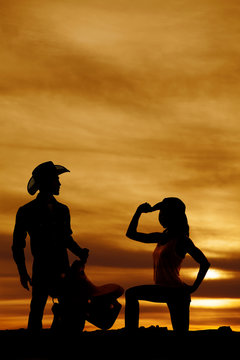 silhouette of a cowgirl kneel on one knee hand on hat