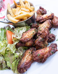 Chicken wings with sauce and golden French fries potatoes