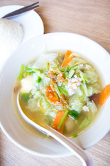 Traditional pork soup served in a white bowl over vegetable back