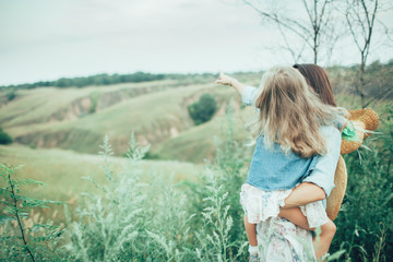 The young mother and daughter on green grass background 