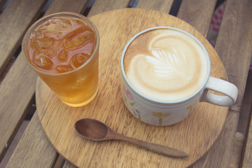 Cup of latte coffee with cold tea on wooden tray