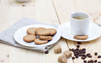 Ginger biscuits, cinnamon, a cup of hot coffee. Walnuts, hazelnuts on a wooden background