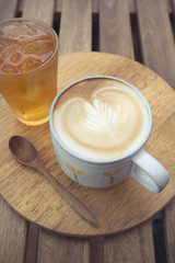 Cup of latte coffee with cold tea on wooden tray