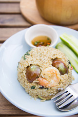 Spicy green curry fired rice with shrimps on wooden table