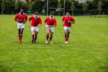 Obraz premium Rugby players jogging with ball