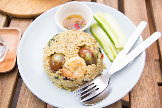 Spicy green curry fired rice with shrimps on wooden table