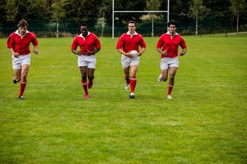 Rugby players jogging with ball