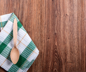white wooden spoon and a towel in the green spot on the wooden b