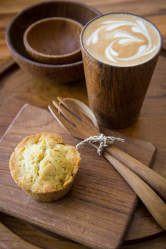 Latte art coffee on wooden cup with pumpkin muffin