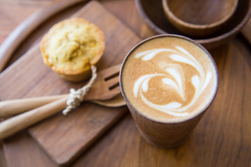 Latte art coffee on wooden cup with pumpkin muffin