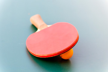 racket for tennis and ball lying on a green table