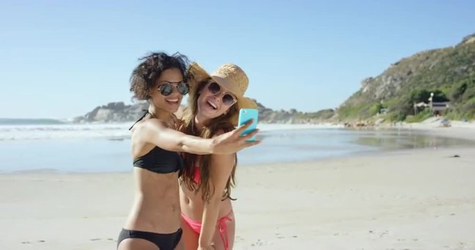 Two friends taking selfies on the beach