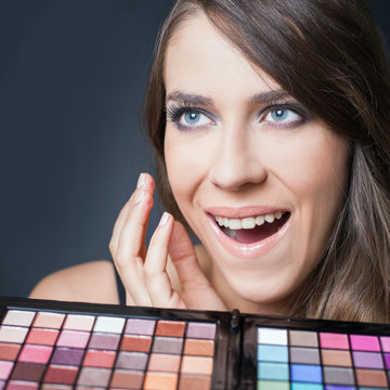 Surprised woman with colorful palette for fashion makeup
