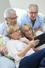 Group of senior friends with eyeglasses using digital tablet