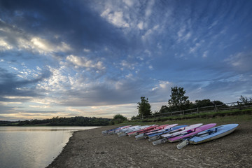 Summer sunset over lake in landscape with leisure boats and equi