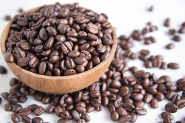 roasted coffee beans in wooden bowl with coffee background