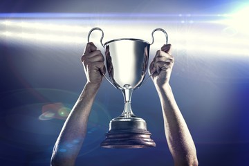 Composite image of successful rugby player holding trophy