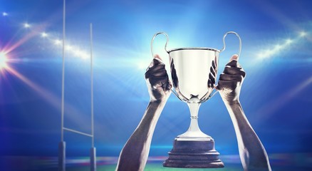 Composite image of cropped hand of athlete holding trophy