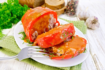 Pepper stuffed meat with sauce and fork in plate on table