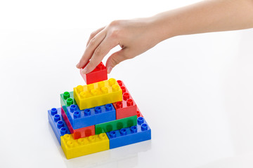 Hand completing colorful plastic brick structure