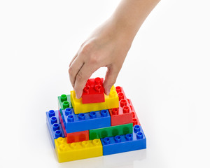Hand completing colorful plastic brick structure