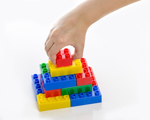 Hand completing colorful plastic brick structure