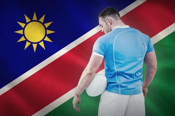 Composite image of rugby player standing with ball