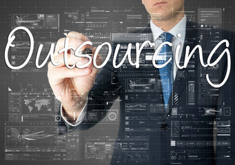 the businessman is writing Outsourcing on the transparent board