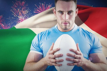 Composite image of rugby player looking at camera with ball