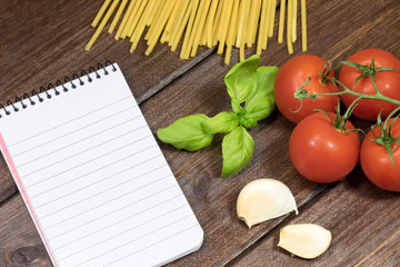 Vegetable, pasta and paper notebook on the wooden table