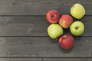 Red and green apples on a wooden desk