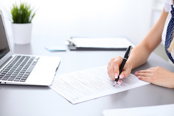 Close-up of female hands with pen over document