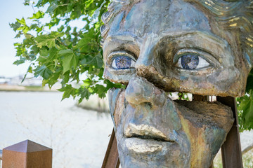 Clay Stone and Steel Sculpture of a Cracked Face with Vibrant Blue Gem Eyes