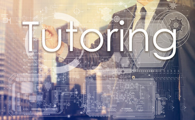 businessman writes on board text: Tutoring - with sunset over th