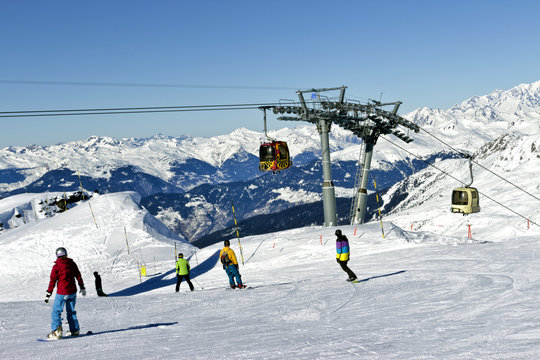 Skiing and snowboarding in high mountains, with ski lift in the background