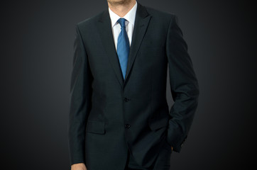 Close up of businessman in suit over dark gray background with c