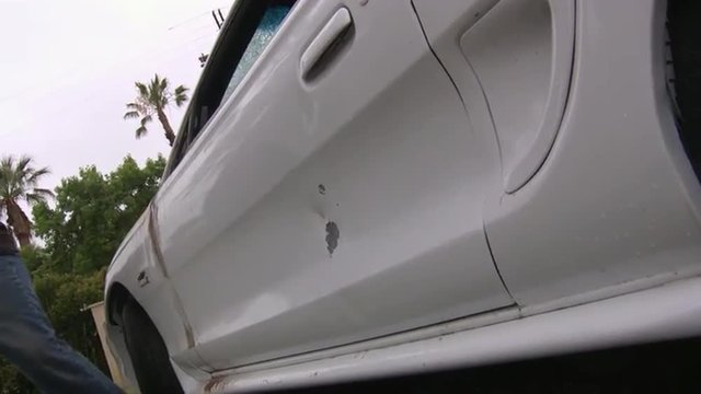 A man destroys his car with a sledgehammer.